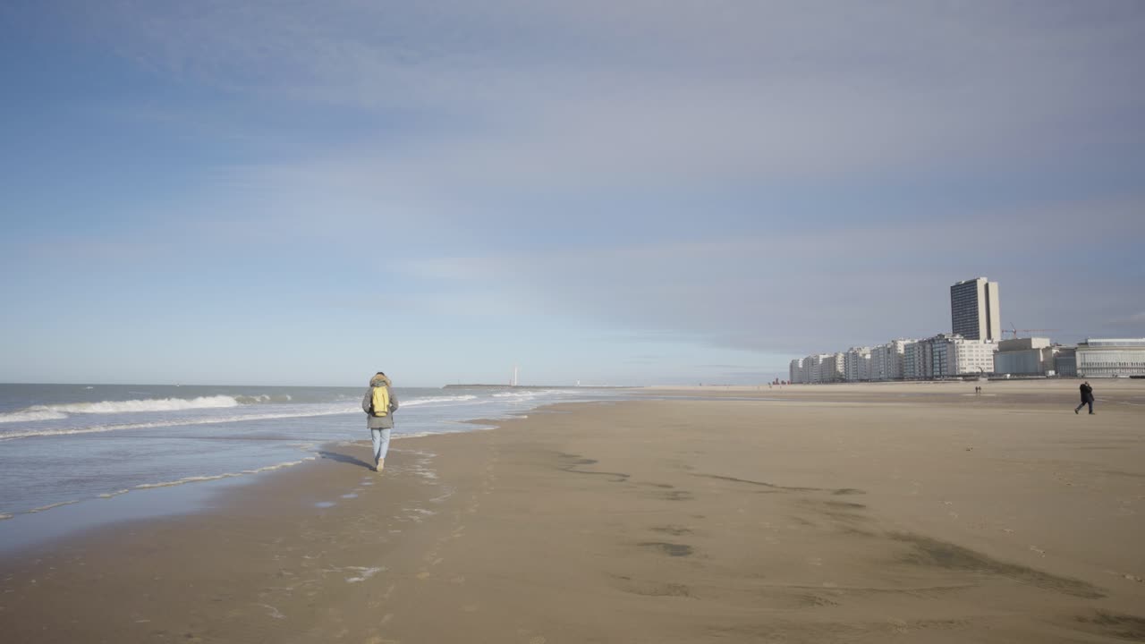 persona solitaria caminando en la playa del mar del norte de ostende, costa de bélgica