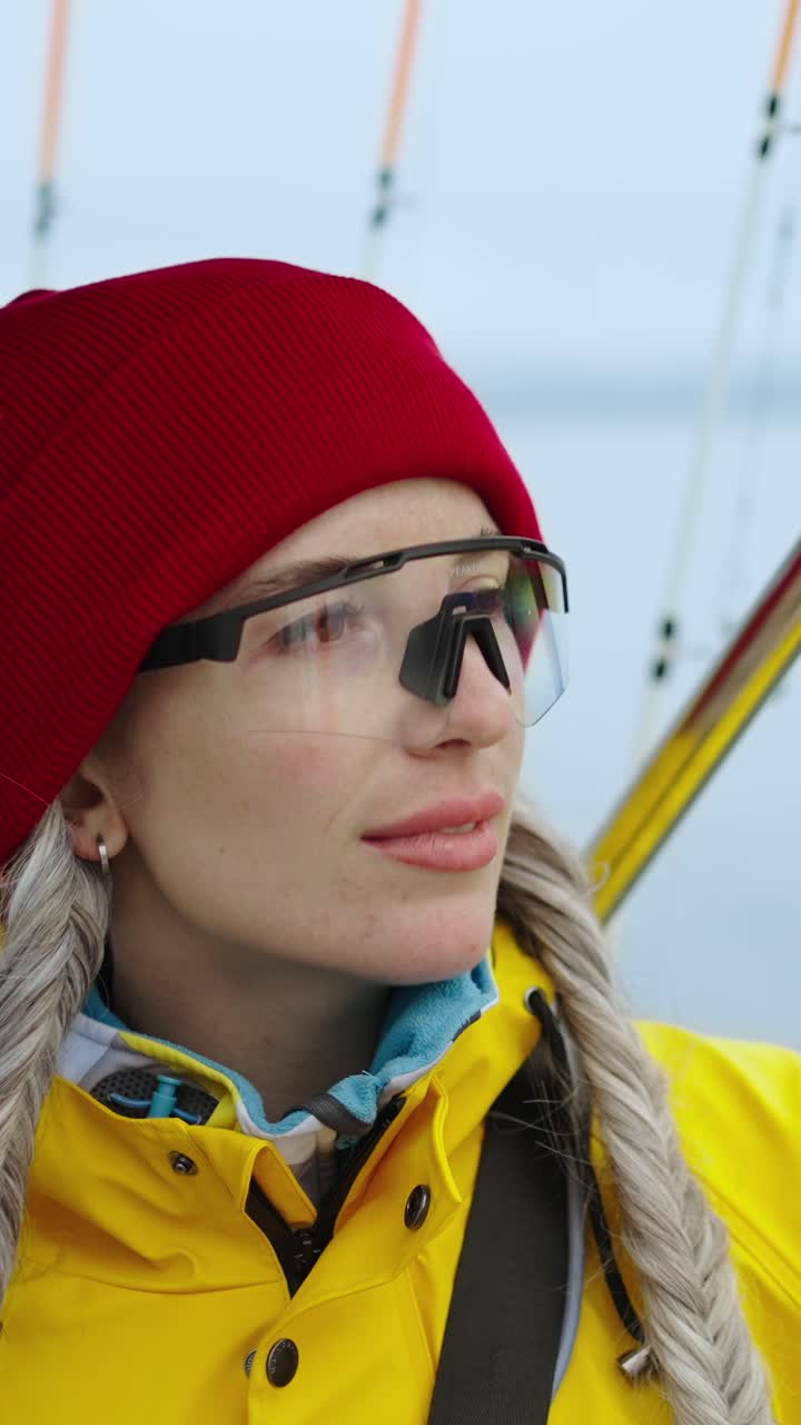 Woman in Red Beanie and Yellow Raincoat Looking Around Outdoors