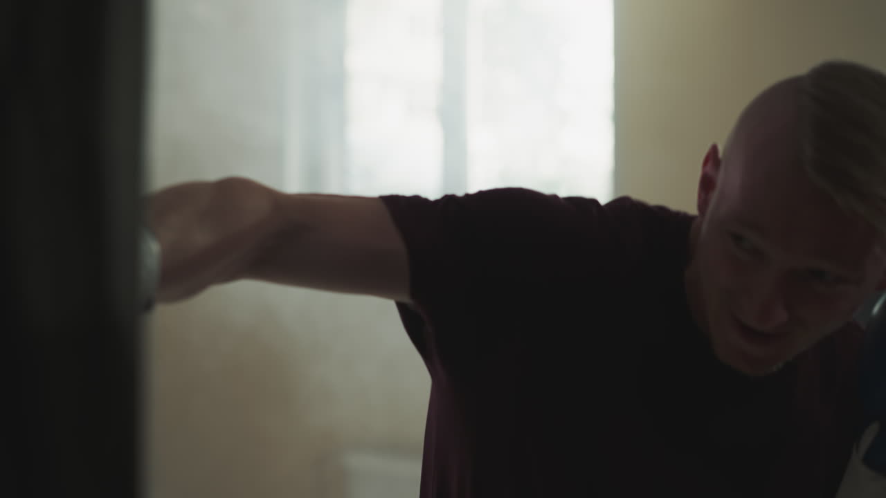 운동선수들이 체육관에서 싱백을 공격합니다. 권투 장갑을 입은 집중된 싸움이 운동 클럽에서 매달린 가방을 때립니다. 느린 동작. 활동적인 생활 방식