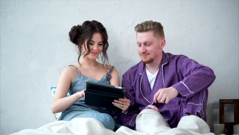 couple relaxing in bed with a tablet