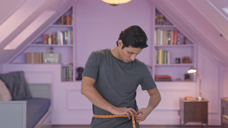 upset indian man measuring waist using inch tape