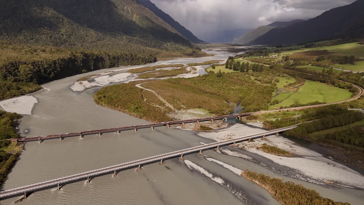 Ponti stradali e ferroviari sul fiume Bealey in uno scenario montano epico, Nuova Zelanda. Vista aerea all'indietro, spazio per il testo