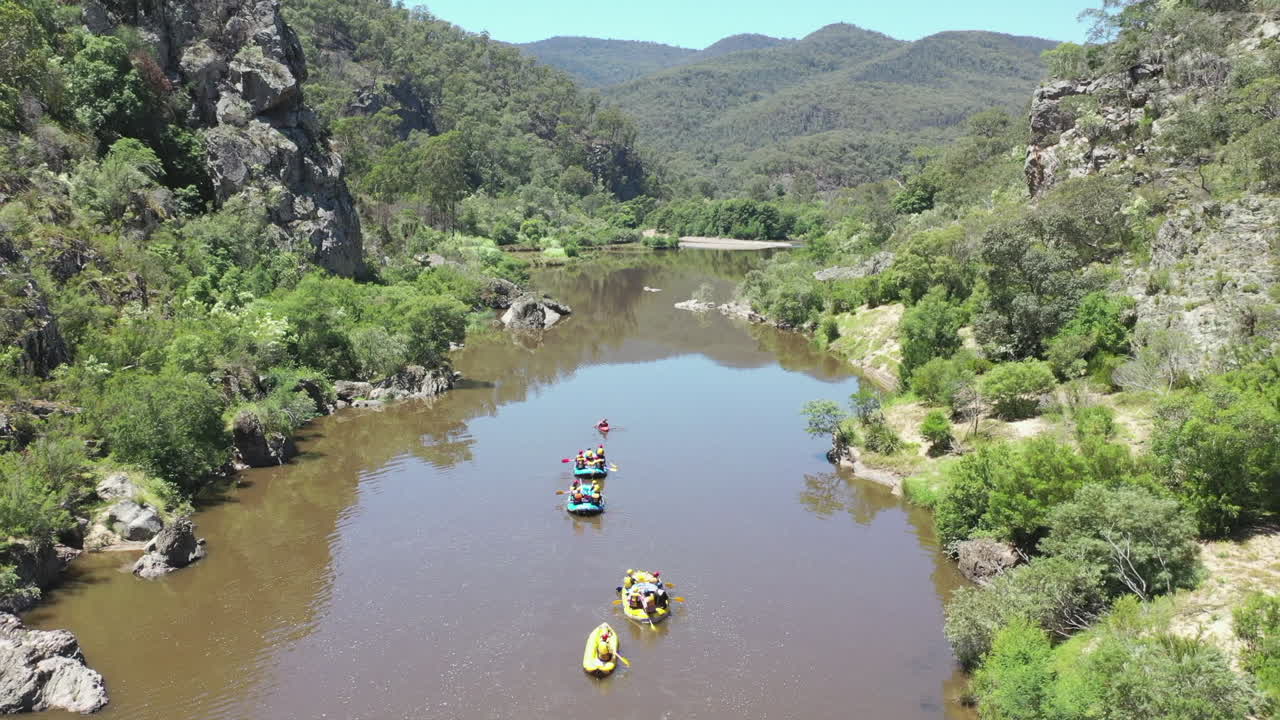 antena: grupo de rafting rema fuera del cañón del río rocoso en aguas planas