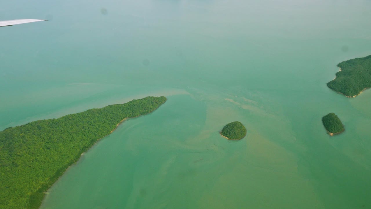 una vista de la ventana del avión superior mientras flota en el aire, con vistas a las montañas y los recursos naturales de agua a lo largo de la costa de tailandia