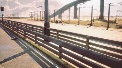 view of a urban road with a fence and distant overpass at midday