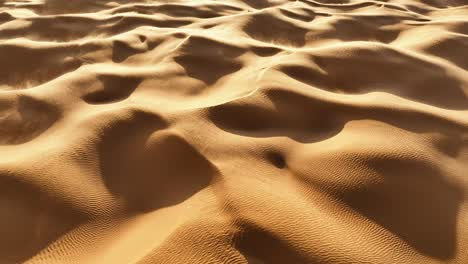 the drone is looking down at the sahara sand rotating with the wind blowing sand over the hills and dunes in tunisia aerial footage 4k