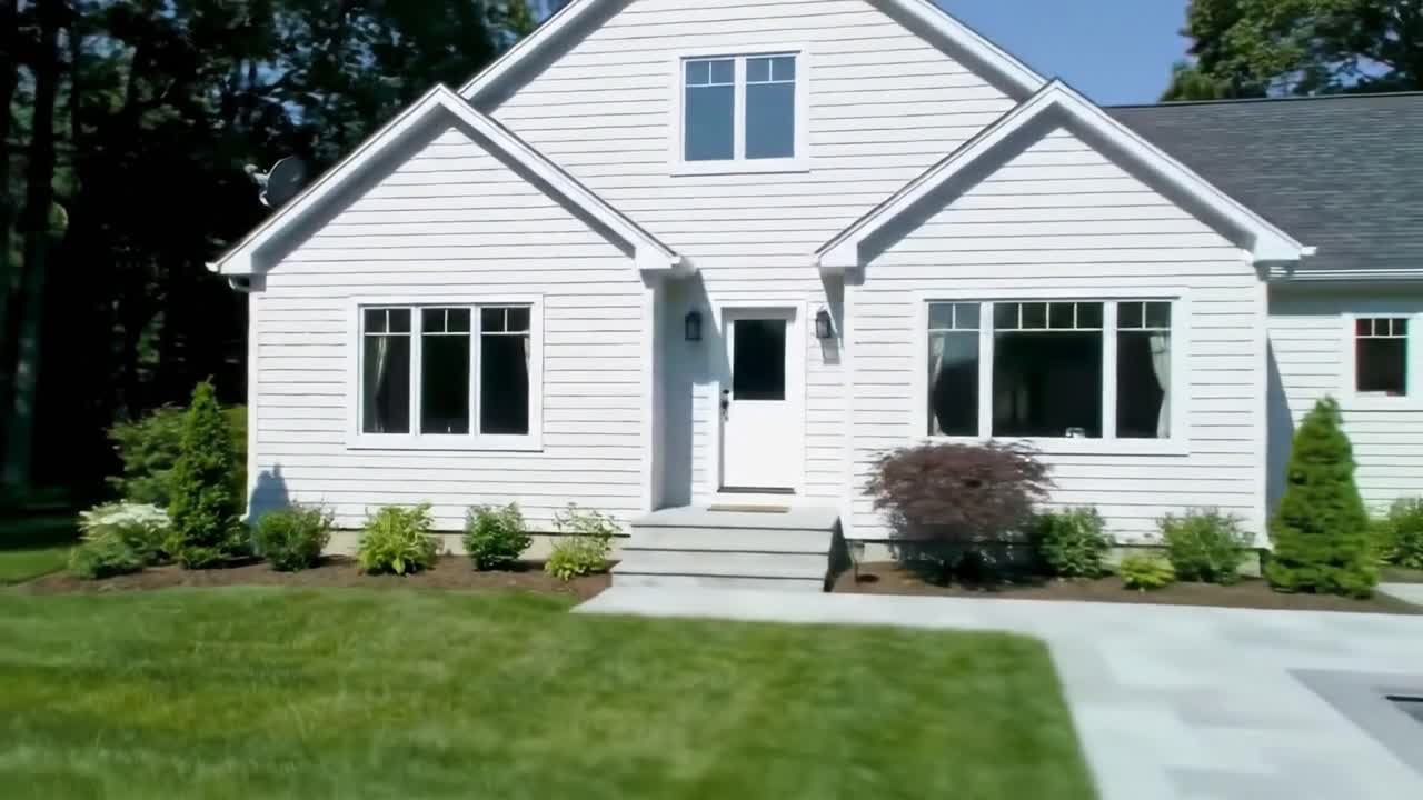 This video showcases a stunning modern house with large windows and a welcoming entrance. The lush green lawn and neatly arranged garden add to the home's charm in a tranquil neighborhood.