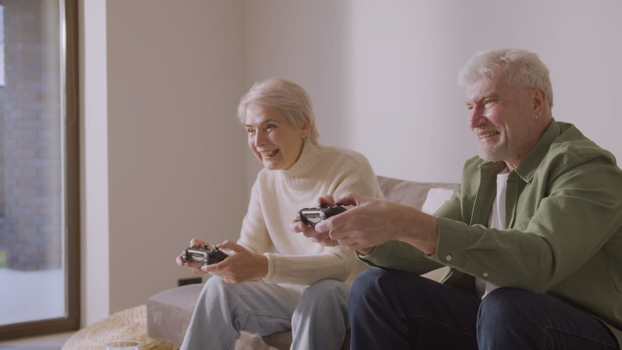 feliz anciano y mujer jugando videojuegos sentados en un sofá en casa 1