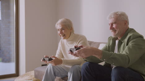 Happy-Senior-Man-And-Woman-Playing-Video-Game-Sitting-On-Sofa-At-Home-1