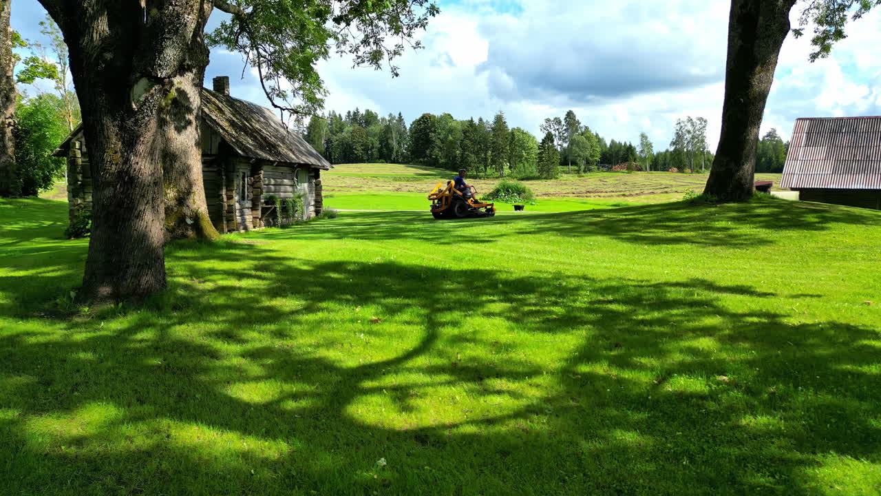 Man Mowing the Lawn on a Sunny Summer Day in the Countryside
