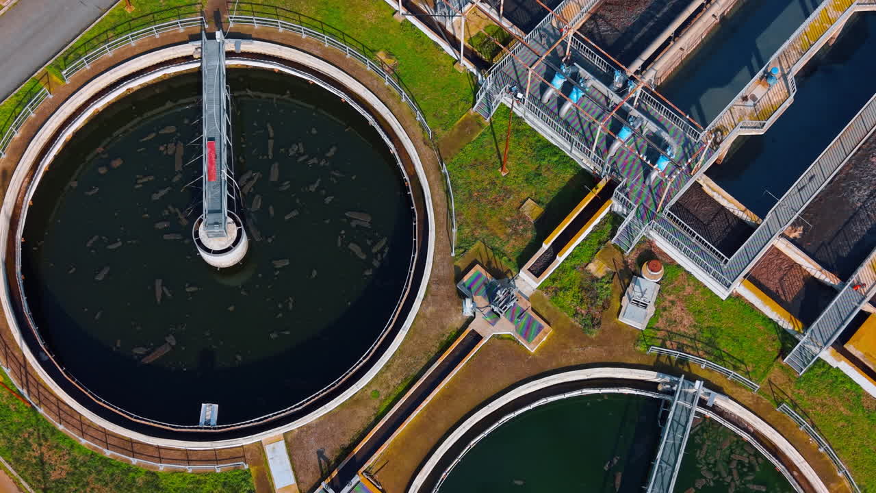 Industrial wastewater treatment plant tanks and aeration systems. Top down view of circular and rectangular clarification tanks with pipes and water filtration systems