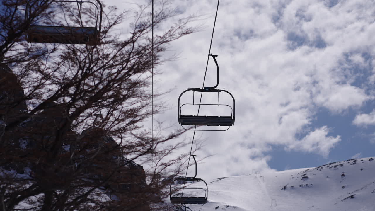 ascensor de esquí de montaña contra un telón de fondo de picos nevados y cielo nublado