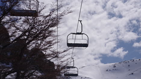 mountain ski lift against a backdrop of snowy peaks and cloudy sky