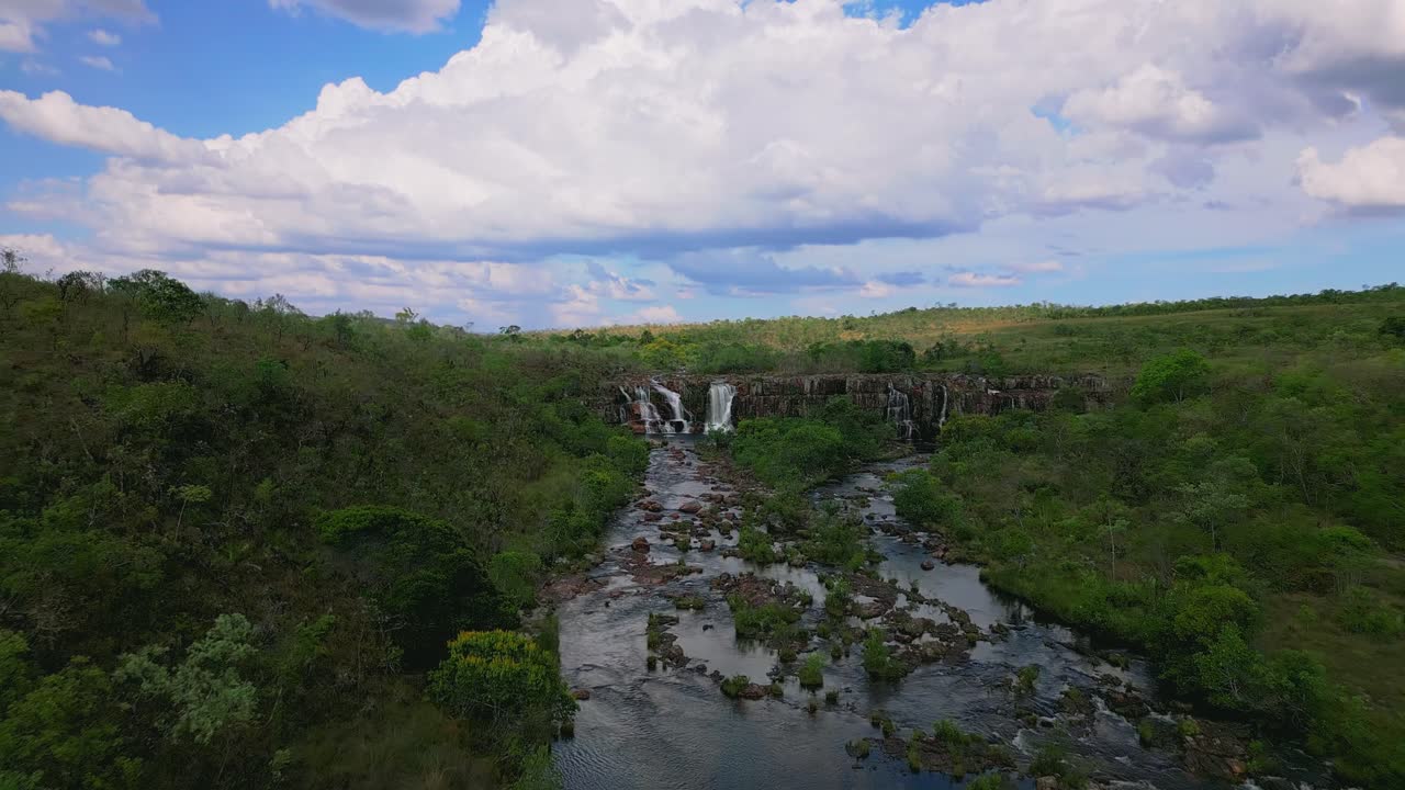 Stunning aerial view of cataratas dos Couros cascading down a rocky riverbed in the lush landscape of Chapada dos Veadeiros national park, Goias, Brazil, under a cloudy sky, drone revealing shot