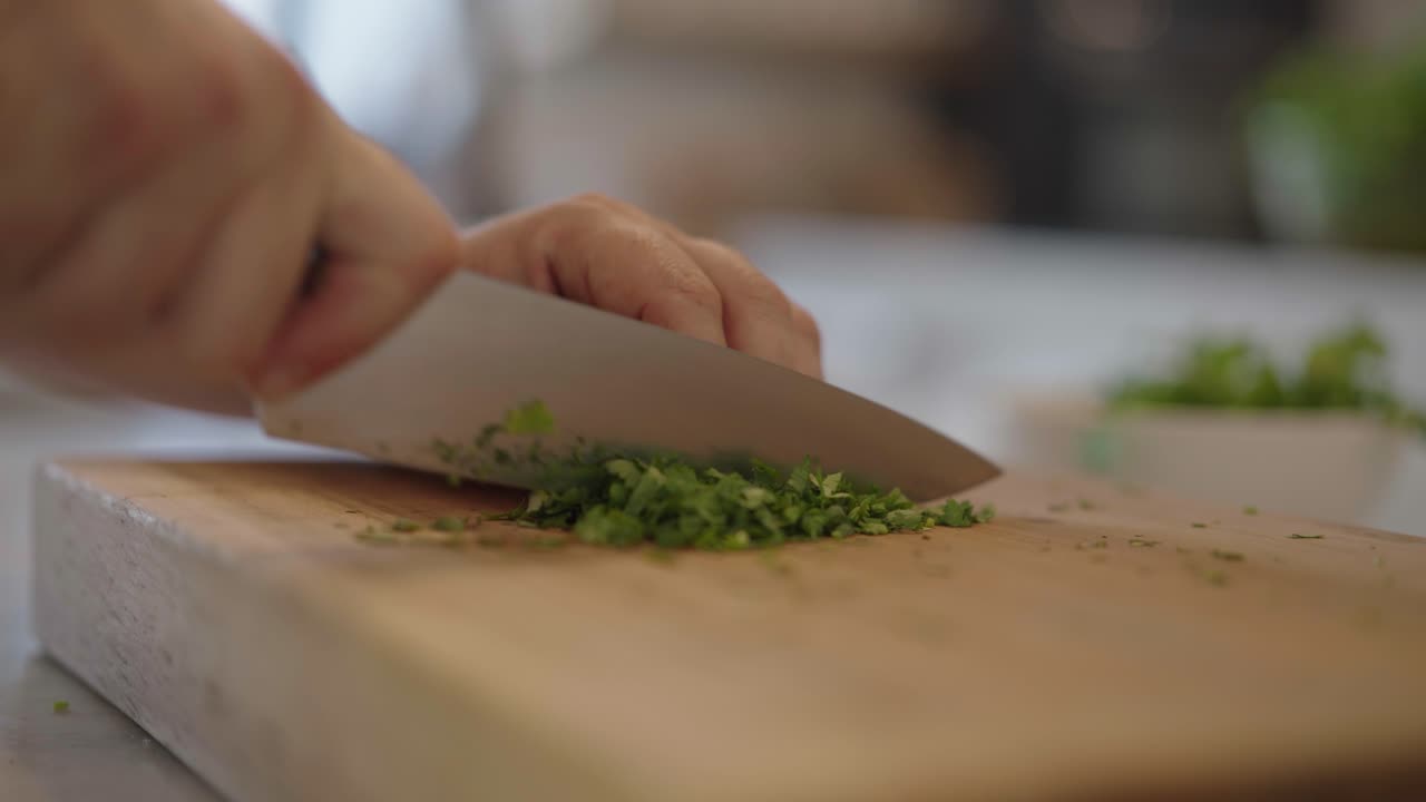 Close up clip of a chef roughly chopping fresh parsley with a sharp knife