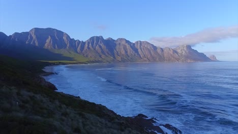 Beautiful-4K-Drone-Shot-Tracking-Over-Rocks-And-Ocean-With-Epic-Kogelberg-Mountain-Range-in-the-back-round