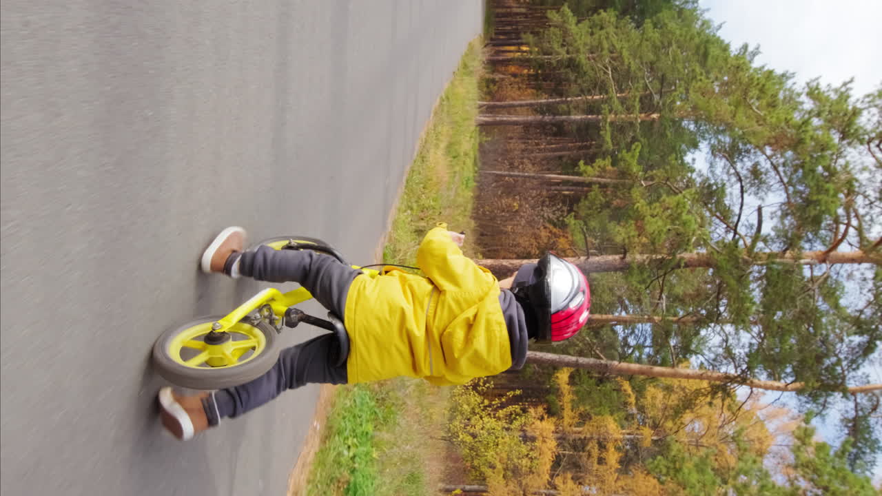 Child riding a balance bike on a road in the forest