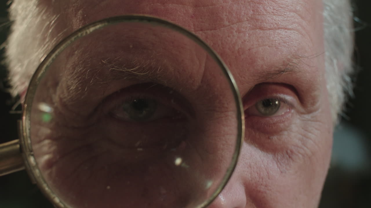 An older man looks through the loupe