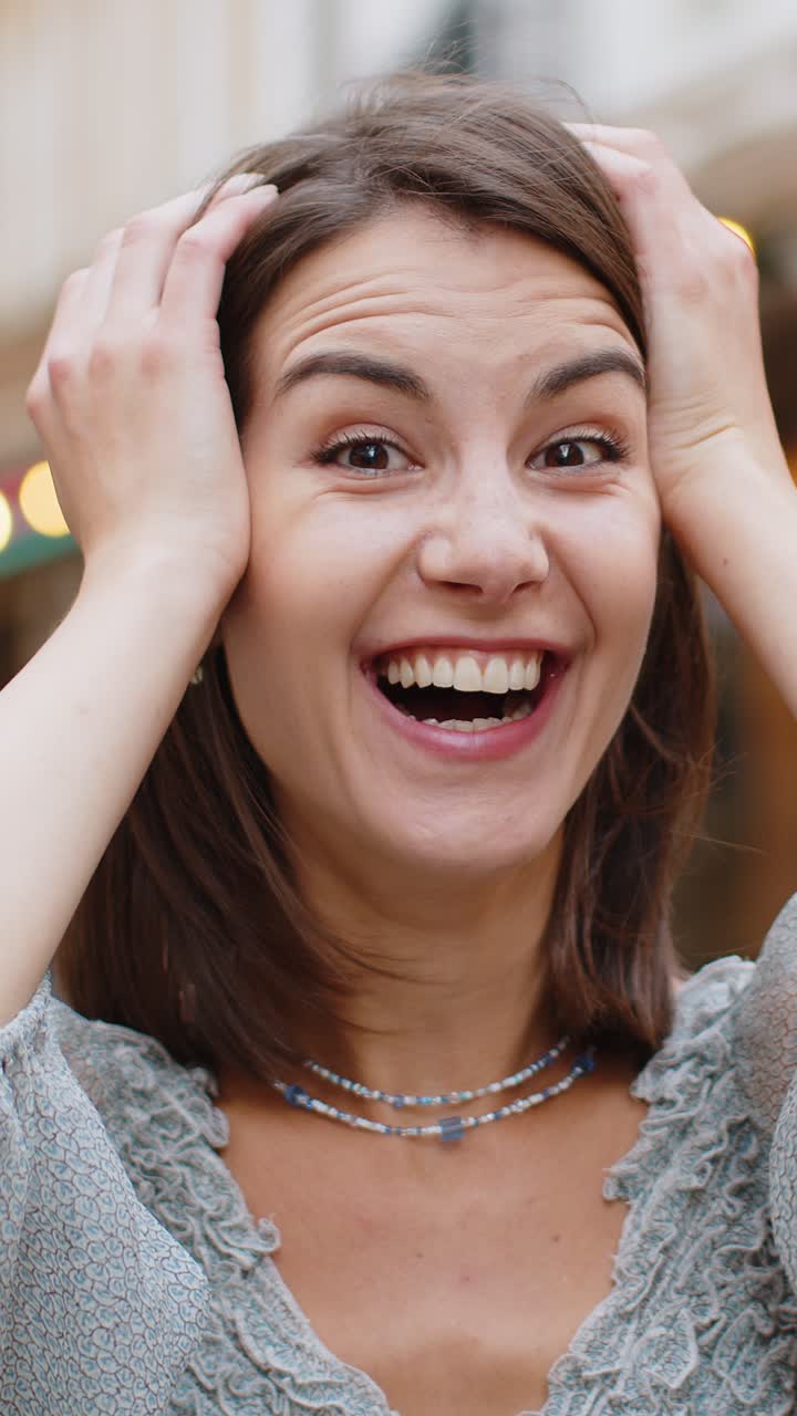 Giovane donna guardando sorpreso alla telecamera scioccato da improvvisa vittoria buona notizia vittoria wow in strada della città