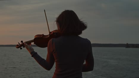 woman is playing violin on sunrise