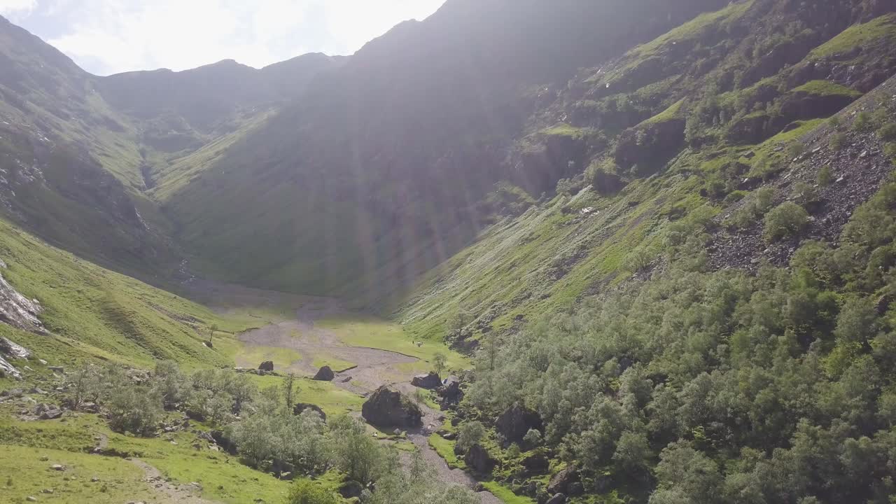 Verde e incontaminata Valle delle Tre Sorelle tra imponenti montagne a Glencoe, Scozia, in una giornata di sole parzialmente nuvolosa.