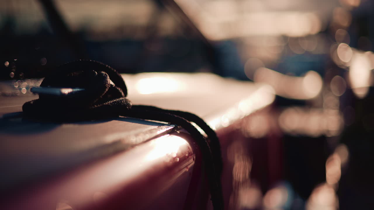 Close up of a boat deck during sunset, with a focus on a black rope coiled on the surface