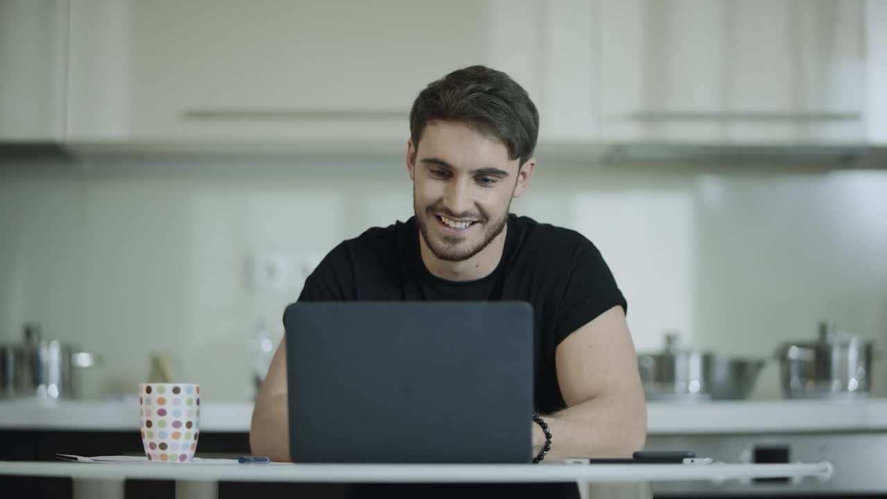 hombre de negocios trabajando en una computadora portátil y bebiendo té en la cocina de casa