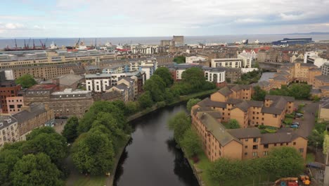 Ein-Sanfter-Drohnenschuss,-Der-Einen-Stadtfluss-Hinunter-In-Richtung-Meer-Fährt-|-Das-Wasser-Von-Leith,-Edinburgh,-Schottland-|-Aufnahme-In-4k-Mit-30-Fps