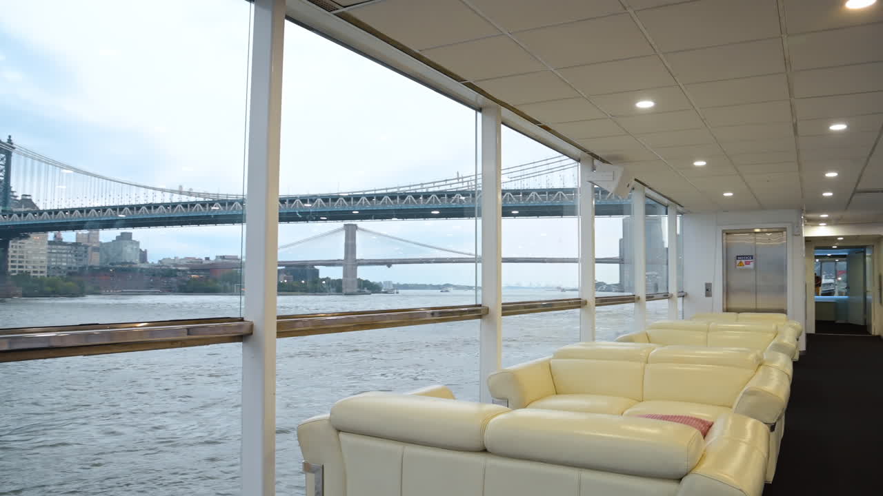 Blick von einer Yacht auf die Manhattan Bridge. Weite Innenansicht einer Yacht mit der Manhattan Bridge und der Skyline des East River durch Panoramafenster