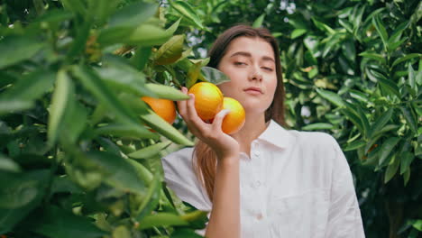 mujer suave posando naranjas en el retrato de la naturaleza verde. niña mirando la cámara