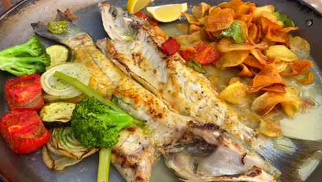gegrillter wolfsbarsch mit knusprigen kartoffeln und gegrilltem gemüse, traditionelle spanische küche in einem restaurant auf ibiza, spanien, 4k-aufnahme