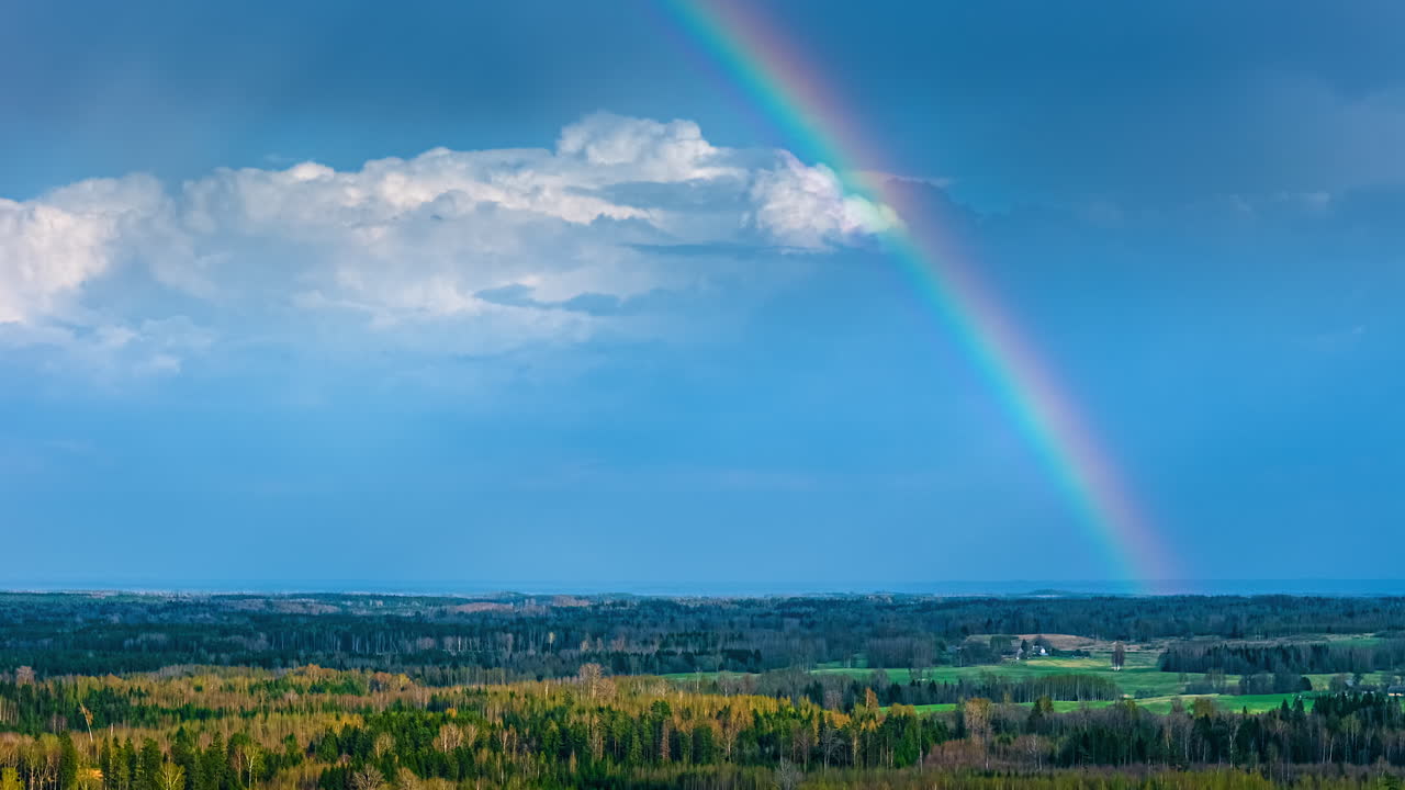 Rainbow timelapse moving clouds over countryside rural forest landscape