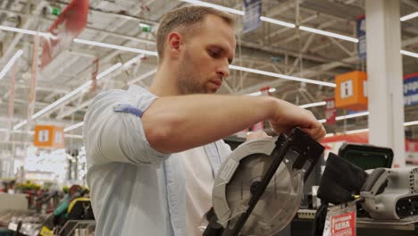 man chooses a circular saw in a tool shop. male select a product in a hardware store