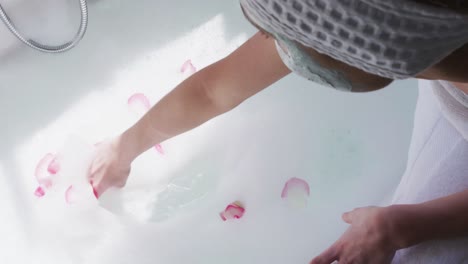 Mid-section-of-woman-spreading-rose-petals-in-the-bathtub
