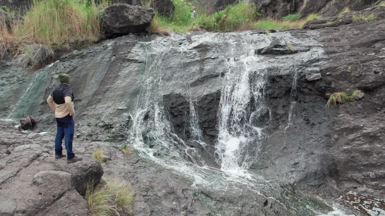 Mannlig turgåer som betrakter El Risco Ravine-fossen i Agaete, Gran Canaria, Kanariøyene