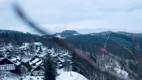 Kleines-Dorf-Mit-Einigen-Schneebedeckten-Häusern,-Die-Durch-Äste-Im-Schnee-Gefilmt-Wurden