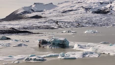 vatnajökull national park, iceland - drone view over fjallsárlón lagoon with snowy peaks, icebergs and glacial reflections, stunning winter wilderness.