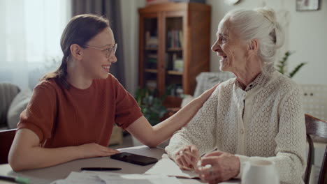 young woman supporting elderly grandmother during paperwork at home