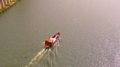 wooden ferry boat cruising in the douro river in porto, portugal