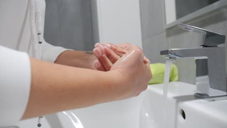 a woman washing her hands with soap in a bright and clean bathroom