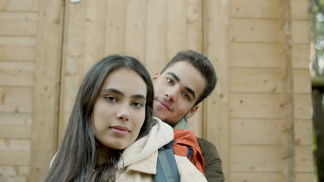 primer plano de una pareja joven posando para la cámara en el porche de una casa de madera en el bosque