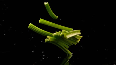 Celery-falling-on-water-against-black-background-4k