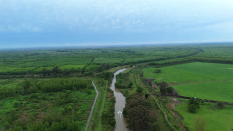 High rising aerial flat green landscape with boat on calm river, Argentina
