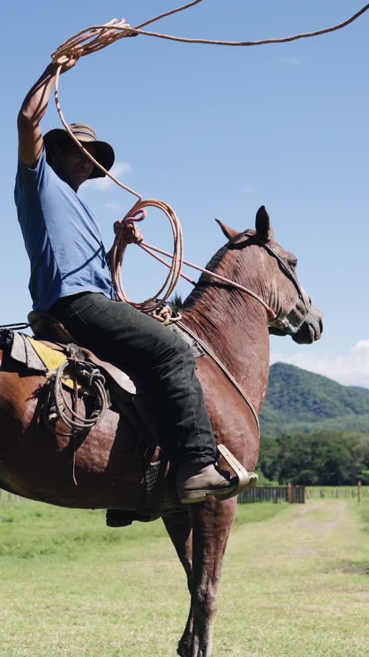 Vaquero a caballo preparándose para lanzar un lazo en un campo rural