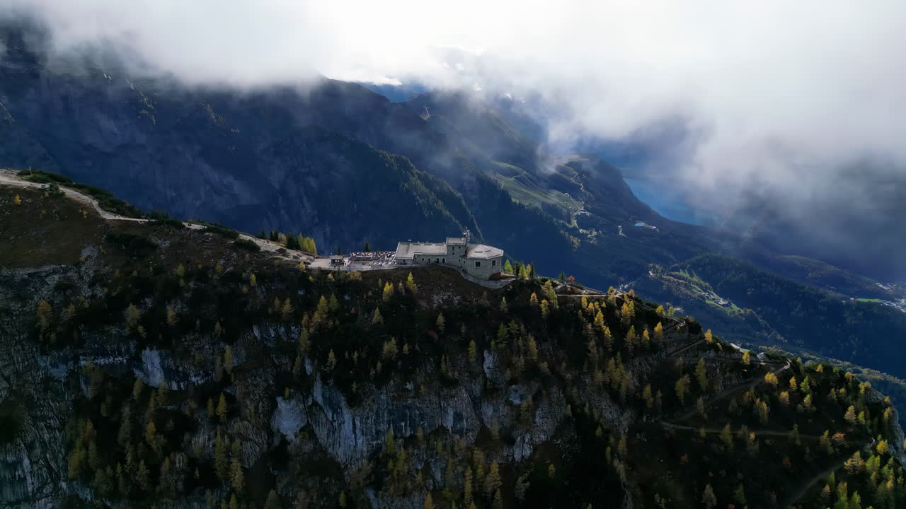 el nido de águila de alemania es un castillo de piedra en el pico de una montaña, rodeado de árboles con hojas de colores.