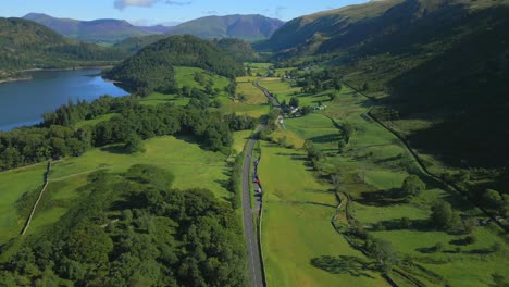 Carretera-Del-Valle-Que-Serpentea-A-Través-De-Una-Exuberante-Campiña-Verde-Junto-Al-Lago-Y-Rodeada-De-Montañas-En-La-Soleada-Mañana-De-Verano-En-Thirlmere,-Distrito-Inglés-De-Los-Lagos,-Cumbria,-Reino-Unido