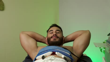 modelo masculino latino mexicano hombre musculoso guapo sonríe mientras recibe el procedimiento de tratamiento lipo láser en el hotel spa centro de bienestar pérdida de grasa