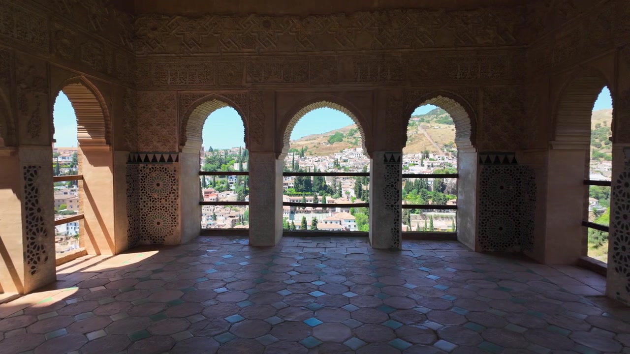 Panoramica al rallentatore attraverso gli archi moreschi ornati all'interno dell'Alhambra, che rivela viste panoramiche di Granada, Spagna, attraverso finestre storiche.