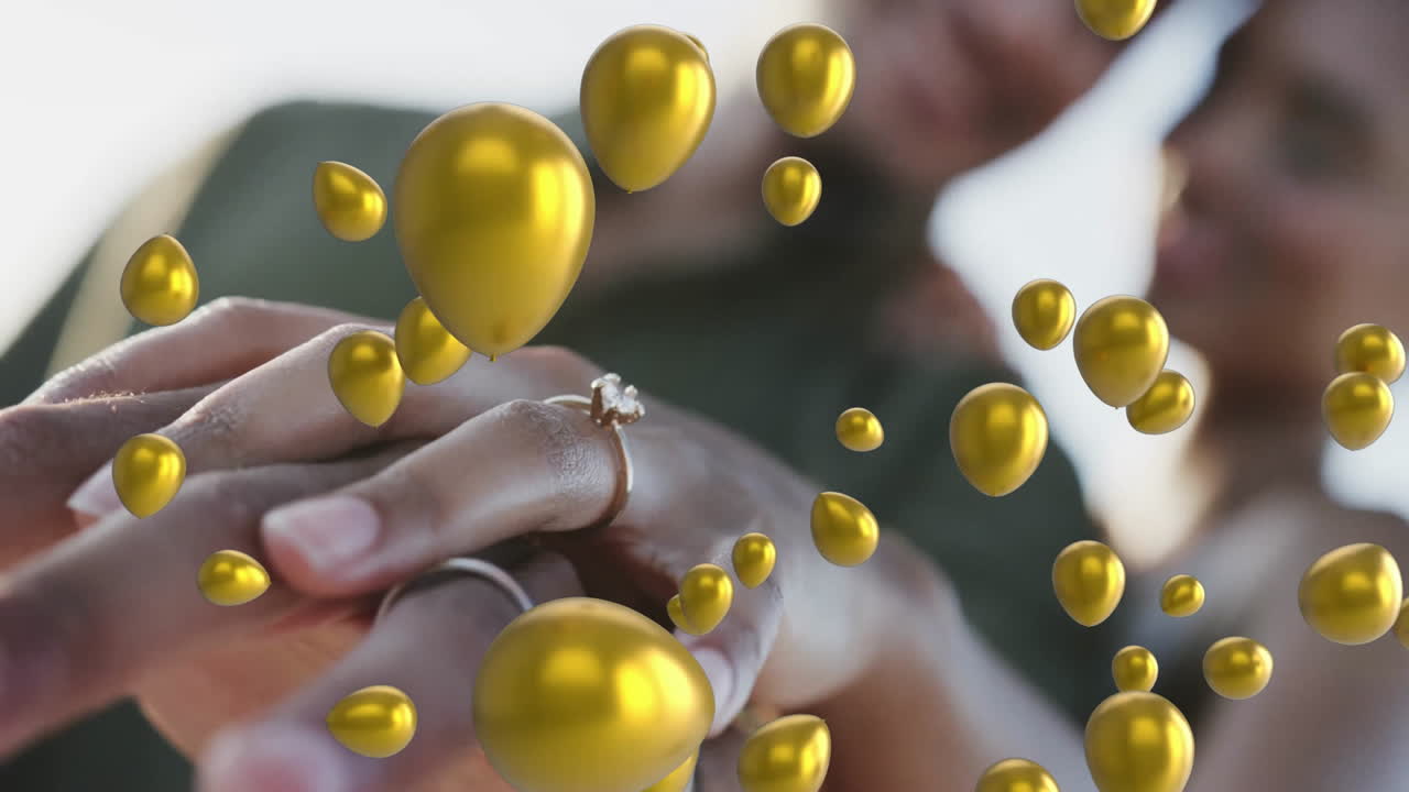 Golden balloons animation over couple holding hands and showing engagement ring
