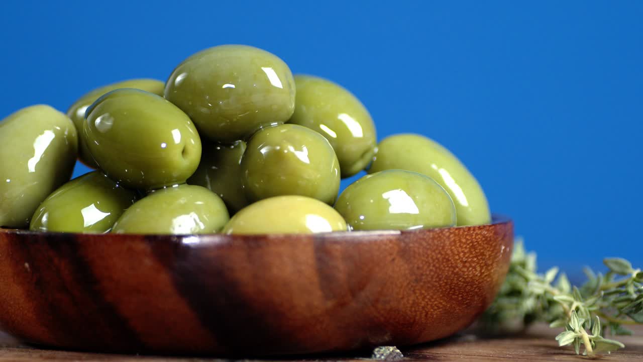 Olives on the plate slowly rotating on the table with thyme.